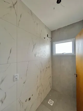 Parede interna com revestimento de mármore claro e uma janela.