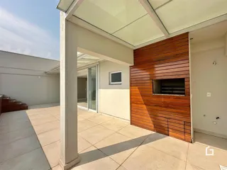 Vista de uma área externa com piso de concreto e parede de madeira.