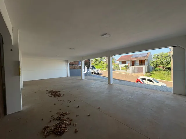Área externa coberta com piso de concreto e vista para a rua.