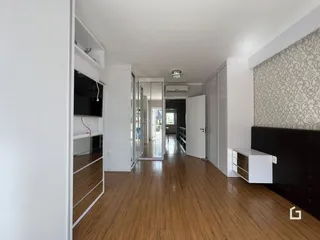 Vista de um corredor interno com piso de madeira e armários em um imóvel.