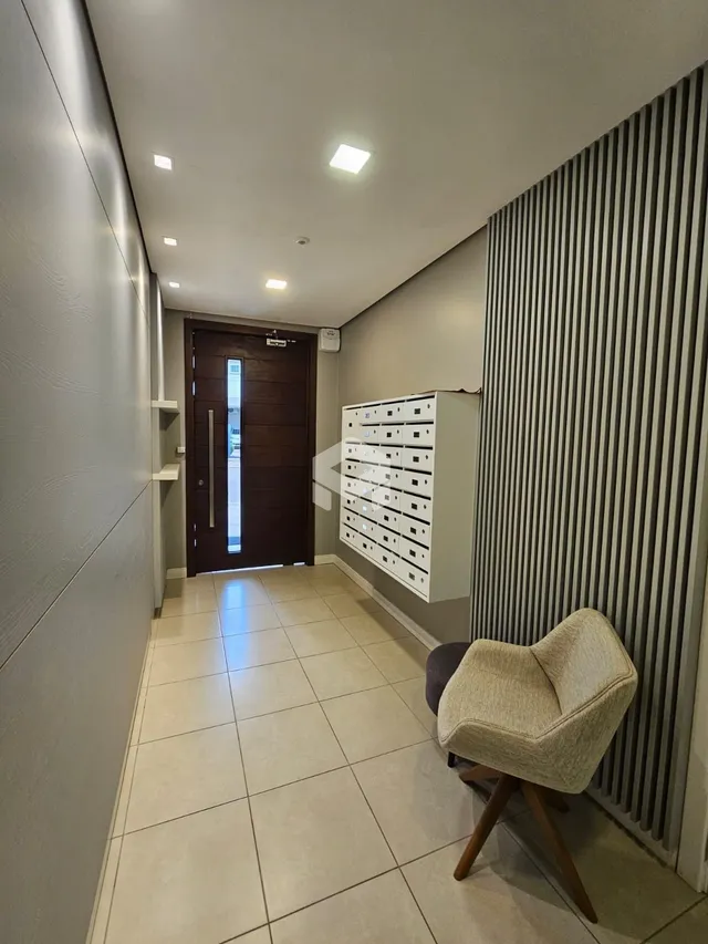 Corredor interno de uma residência com piso de cerâmica clara.