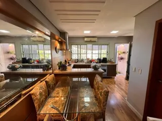 Uma sala de jantar com mesa de vidro e cadeiras em um imóvel.