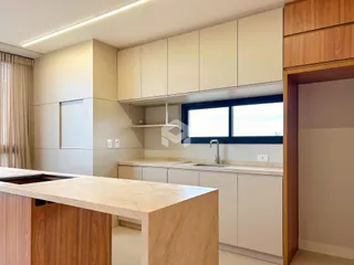 Vista interna de uma cozinha moderna com armários brancos e bancadas claras.