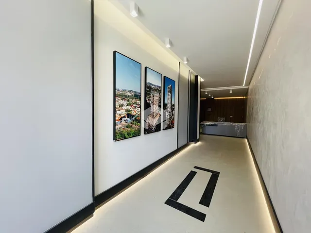 Corredor interno de um imóvel moderno com paredes brancas e iluminação embutida.