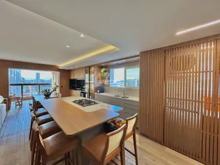 Área de jantar com mesa de madeira e acabamentos modernos em um imóvel.