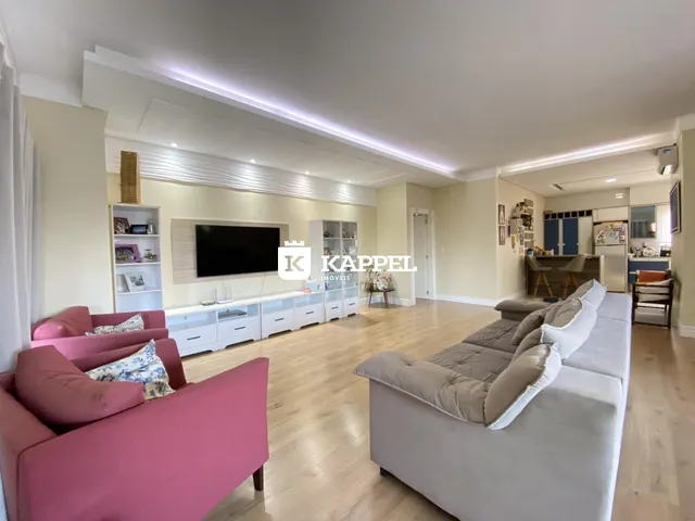 Sala de estar ampla com sofás e piso de madeira clara.