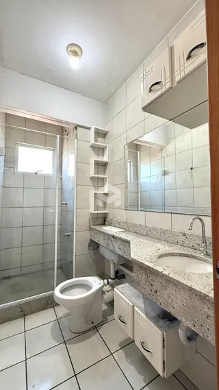 Banheiro com revestimento cerâmico e box de vidro.