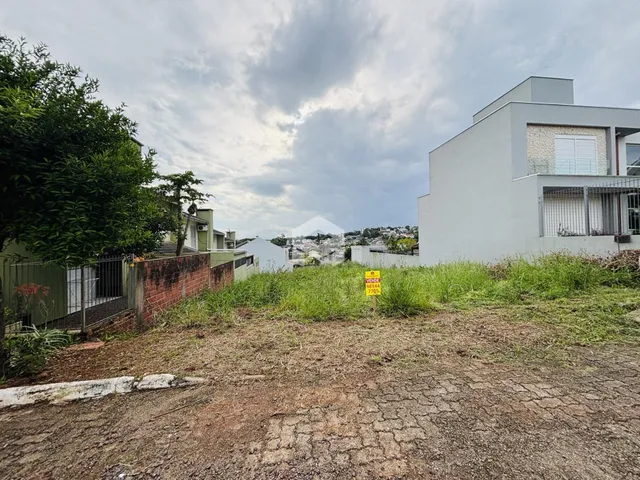Vista da fachada de uma propriedade com vegetação e cerca no primeiro plano.