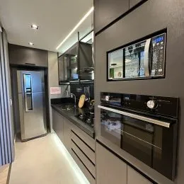 Cozinha moderna com armários escuros e eletrodomésticos em aço inoxidável.