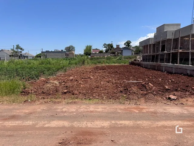 Imagem de um terreno com vegetação e construção ao fundo.