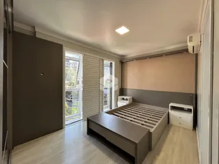 Quarto moderno com piso de madeira clara e grande janela.