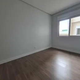 Foto de um cômodo com piso de madeira e parede branca.