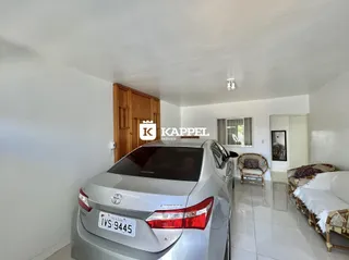 Foto interna de uma sala com armários de madeira e um veículo estacionado.