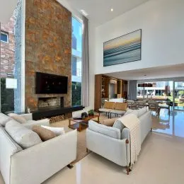 Sala de estar com sofá branco e lareira em ambiente interno.