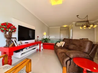 Sala de estar com sofá marrom e televisão montada na parede.