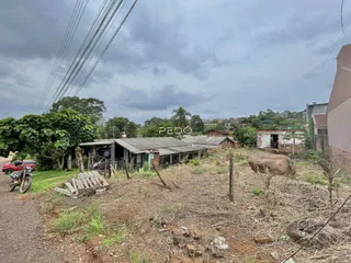 Vista externa de uma propriedade com estruturas rústicas ao fundo.