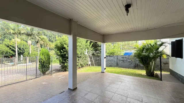 Área externa pavimentada com vista para o jardim.