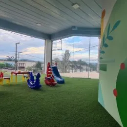 Vista externa com gramado verde e paisagem ao fundo.