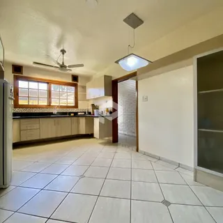 Foto interna de uma cozinha com piso de cerâmica clara e armários brancos.