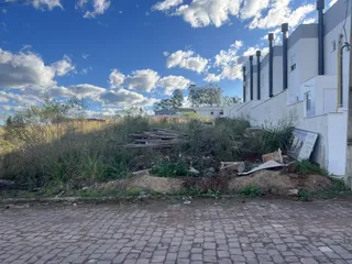 Foto da fachada de um imóvel branco com tubulações pretas sob um céu azul.