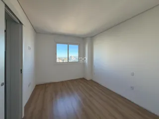 Ambiente interno com piso de madeira e janela de vista para a cidade.