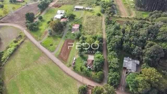 Vista aérea de terras rurais com vegetação e estradas de terra.
