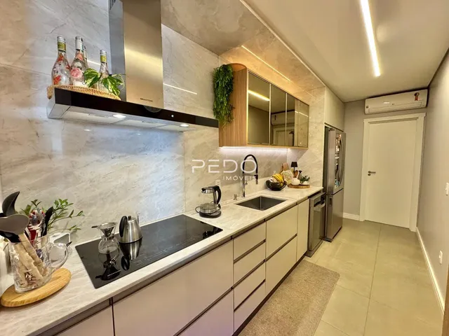Cozinha moderna com armários e bancadas de mármore.