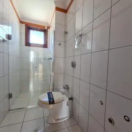 Foto interna de um banheiro com revestimento de azulejos brancos.
