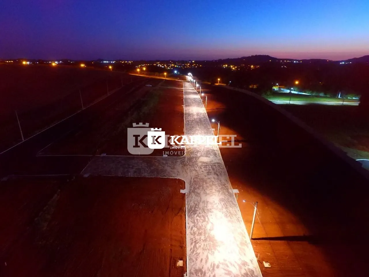 Vista aérea de uma estrada rural com iluminação noturna ao entardecer.