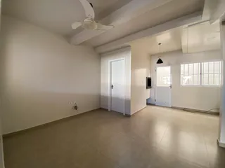 Foto de uma sala ampla e vazia com paredes brancas e piso claro.