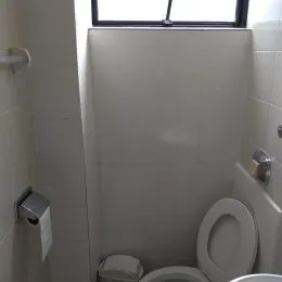 Foto de um banheiro com revestimento branco e vaso sanitário.