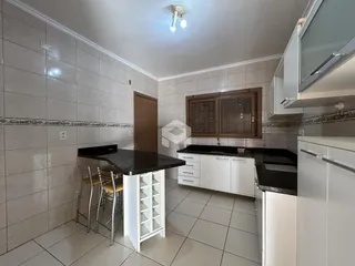 Vista interna de uma cozinha com ilha e revestimento de cerâmica.