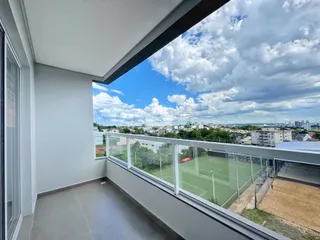 Vista da varanda com vista para a cidade e um campo esportivo.