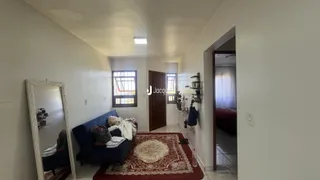 Hall de entrada com sofá azul e tapete vermelho em um apartamento.