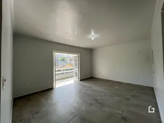 Vista interna de uma sala ampla com piso de porcelanato claro.