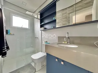 Banheiro moderno com box de vidro e bancada de pia.