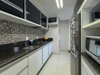 Cozinha com bancadas de granito escuro e armários brancos.