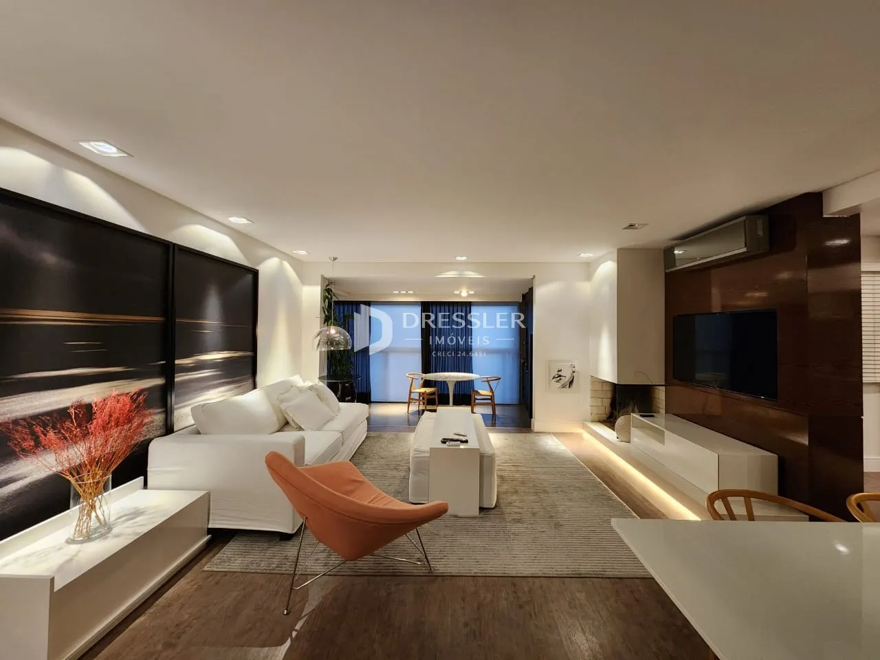 Sala de estar moderna com sofá branco e piso de madeira.