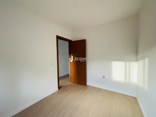 Hall de entrada com piso de madeira clara e porta de madeira escura.