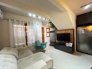 Sala de estar com sofá branco e janelas claras em um imóvel no Brasil.