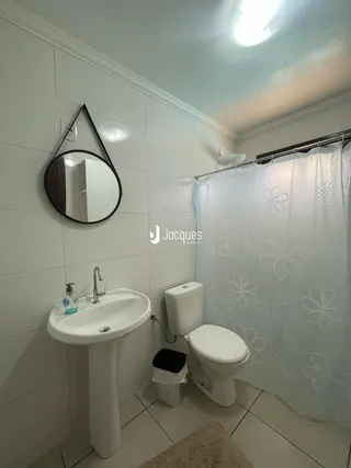 Foto de um banheiro com azulejos brancos e cortina de banho clara.
