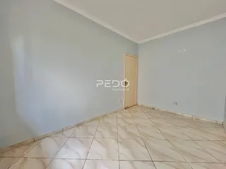 Vista interna de um cômodo com piso de cerâmica e uma porta de madeira.