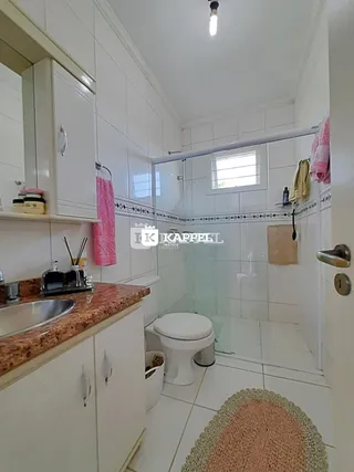 Foto de um banheiro com box de vidro e revestimento branco.