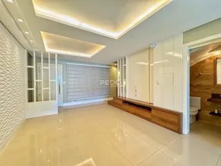 A sala de estar apresenta um piso claro e paredes brancas com iluminação embutida.