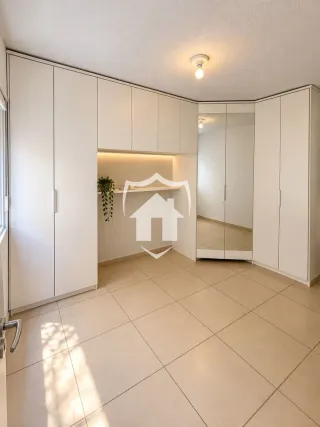 Ambiente interno com armários brancos e piso de cerâmica claro.