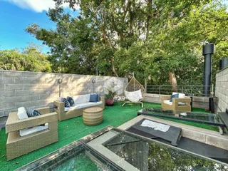 Vista de um pátio externo com mobiliário de jardim e vegetação.