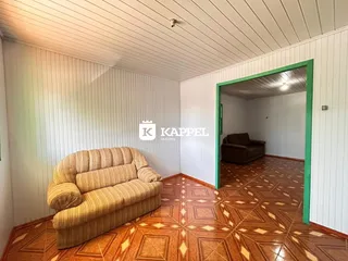 Sala de estar com sofá bege e piso de madeira.