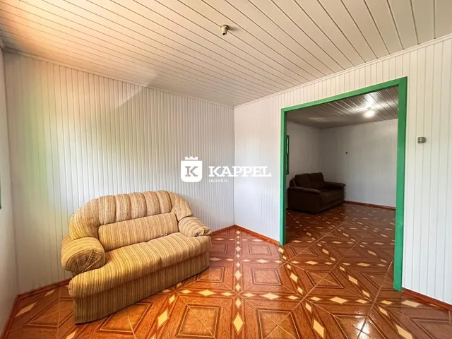 Sala de estar com sofá bege e piso de madeira.