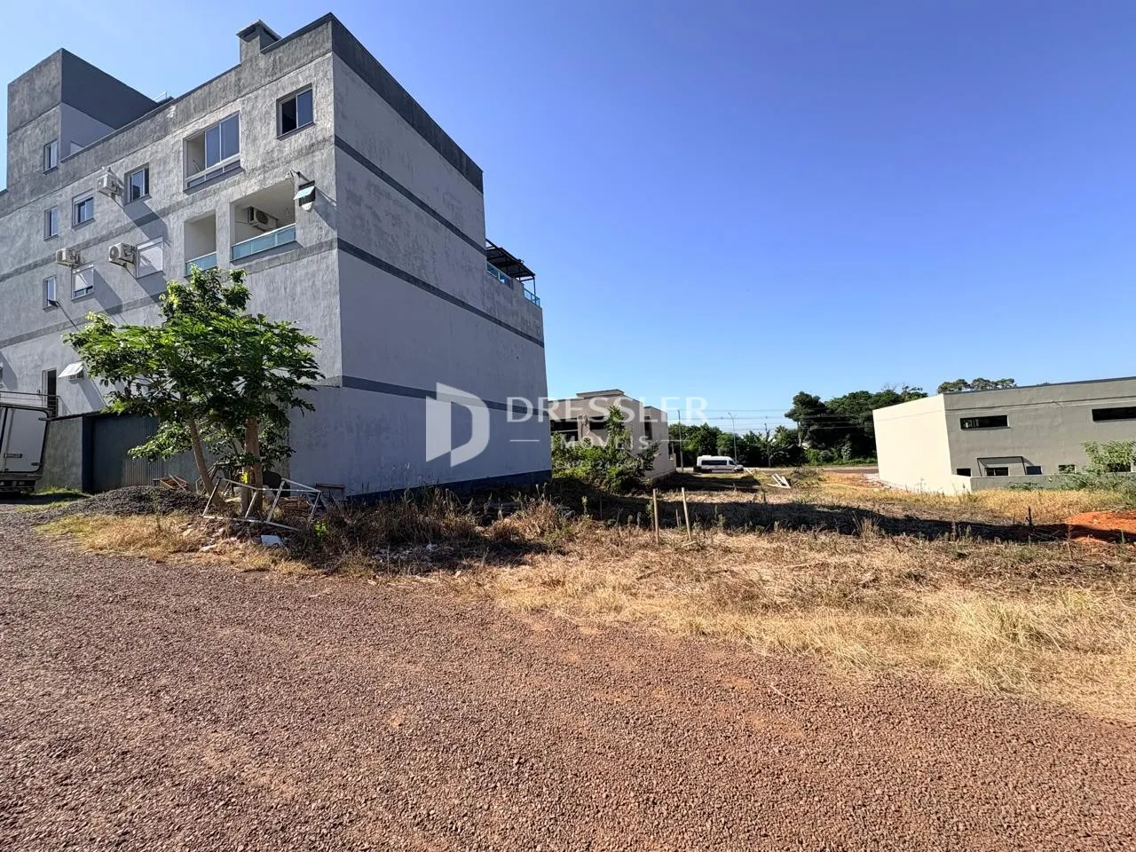 Fachada de um prédio residencial em Lajeado, Brasil, com vegetação seca no primeiro plano.