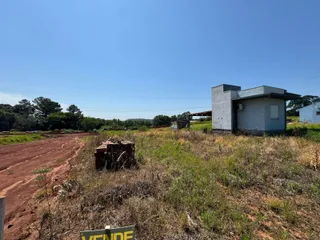 Vista externa de uma construção simples em uma área rural com vegetação seca.
